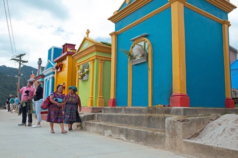 Mayan woman wearing traditional clothing at colorful graves at the cemetery in Chichicastenango,