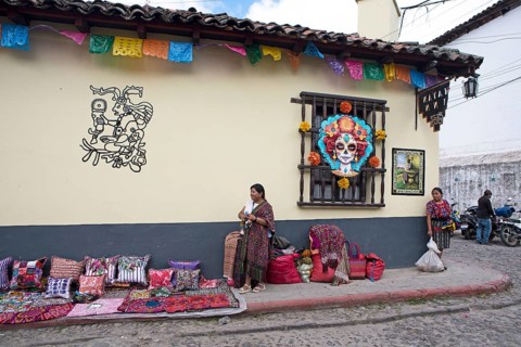 Mayan woman wearing traditional clothing on a decorated house façade, Chichicastenango market,