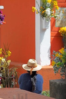 Mayan woman wearing straw hat looking at a colorful grave in the cemetery in Chichicastenango,