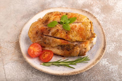Fried Turkey Thigh with spices and rosemary on plate on brown concrete background. side view, close