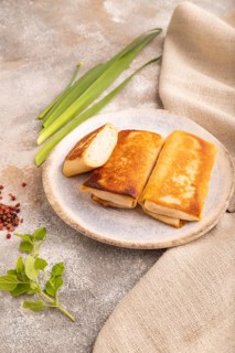 Fried crispy pancakes with meat and cheese on brown concrete background and linen textile. side