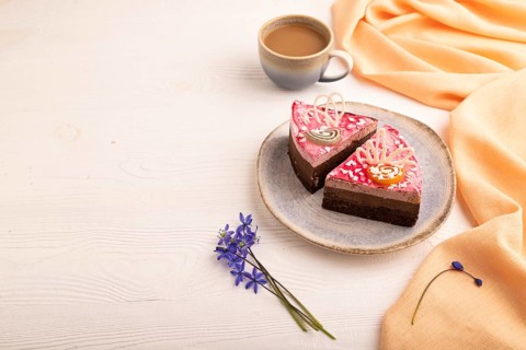 Chocolate cake on white wooden background and orange linen textile, cup of coffee, side view, copy
