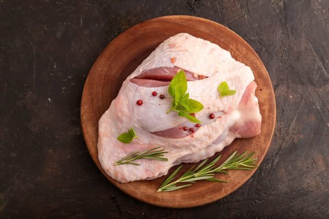 Raw Turkey Thigh with spices and rosemary on cutting board on black concrete background. top view,