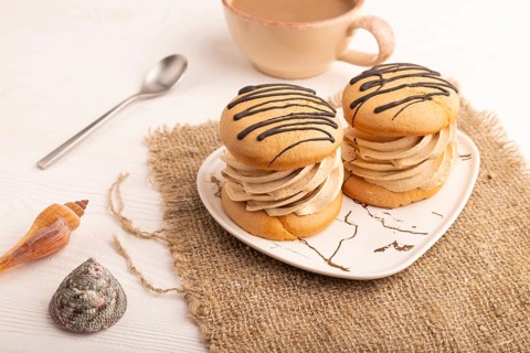 Caramel Cream Cakes on white wooden background and linen textile, cup of coffee, side view, close