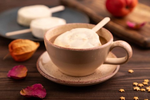 ?hocolate Ice cream in white glaze, cup of coffee, on brown wooden background, side view, close up,