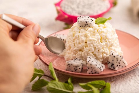 White ?ottage cheese, Curd, with Pithaya with hand on gray concrete background and linen textile,