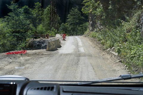 Narrow dirt road leads through wooded mountains, road 7 partly slipped down, west of Mestia,