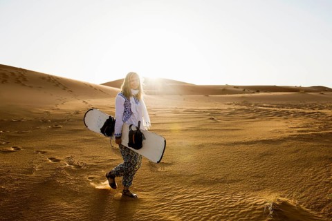 Young woman with snowboard in the sand dunes, near Merzouga, Meknès-Tafilalet region, Erg Chebbi,