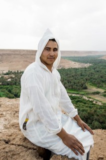 Young man and oasis in the background, near Merzouga, Meknès-Tafilalet region, Erg Chebbi, northern