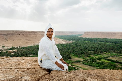 Young man and oasis in the background, near Merzouga, Meknès-Tafilalet region, Erg Chebbi, northern
