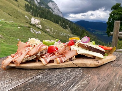 Typical snack on the alpine pasture, bacon bread and cheese bread on wooden plate on wooden table,