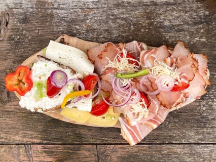 Typical snack on the alpine pasture, bacon bread and cheese bread on wooden plate on wooden table,