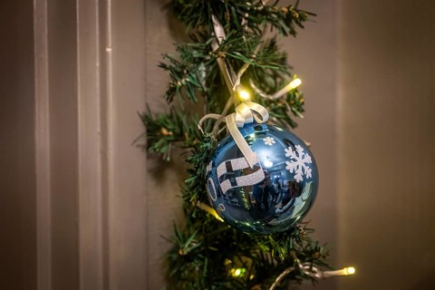 Blue Christmas ball with Finland flag and snowflakes, fairy lights, pine branch, Finland
