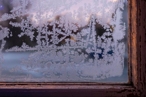 Window with old window frame and frosty ice crystals in the evening light, Finland