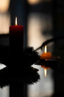 Two candles stand on a table in front of a window at dusk and create a Christmas atmosphere,