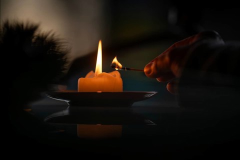 Hand still holding a burning match after a yellow candle is lit, Christmas atmosphere, Finland