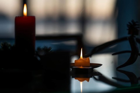 Two candles stand on a table in front of a window at dusk and create a Christmas atmosphere,
