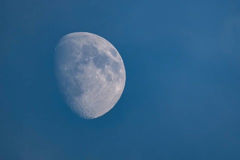 Detailed image of the waxing moon with visible craters and spots during the day, dividing line