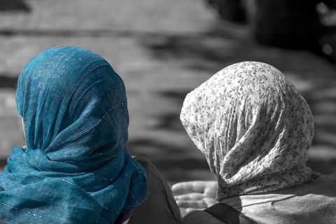 Two woman wearing headscarves talking on a bench, black and white, Paris, France