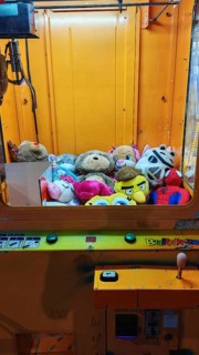 Automatic grappling machine full of colorful stuffed animals in a yellow case, Batumi, Georgia
