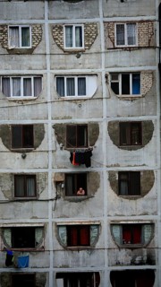 Dilapidated residential building with open windows and people in a simple environment, Tbilisi,