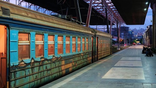 Night view of an illuminated train in a railway station with urban surroundings, Yerevan, Armenia