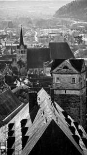 Black and white photo of a town with church tower and historic buildings, view over the roofs of