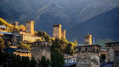 Village with historic towers and mountains in the background at sunset, Mestia, Georgia