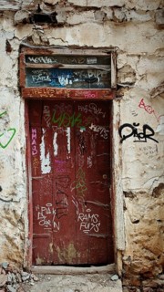 Old red door with graffiti in a weathered building, abandoned atmosphere, Ohrid, North Macedonia