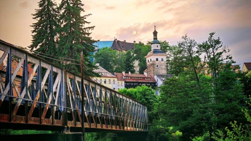 Scenic city view with bridge, historic buildings and trees at dusk, Loket, Czech Republic
