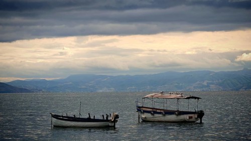Two small boats float on a calm lake under a dramatic sky, Lake Ohrid, North Macedonia