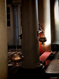 A quiet church interior with tall pillars and a hanging incense barrel in a play of light,