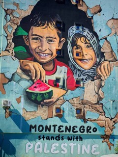 Wall painting of laughing children with text in support of Palestine