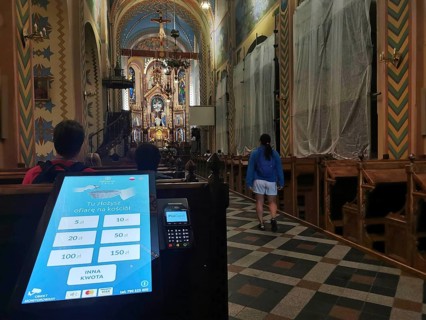 Church interior with decorative altar, visitors and donation machine