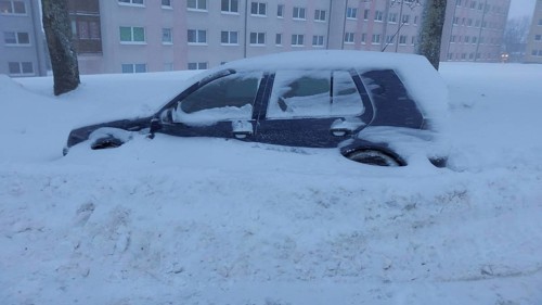 Snowy car parked in urban area after snowfall