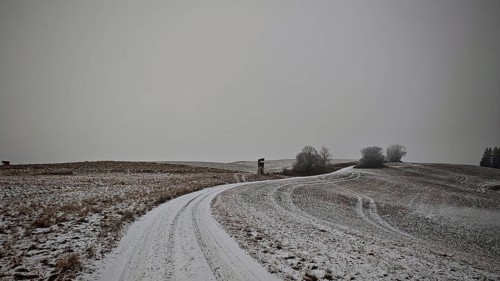 Snowy field with a winding path and grey sky, Franconian Forest nature park Park