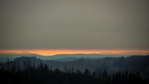 Twilight landscape with looming hills and trees under a cloudy sky