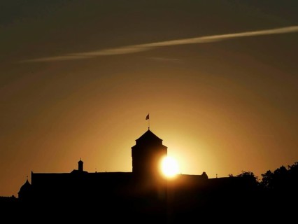 Castle silhouette in front of a sunset with golden sun on the horizon