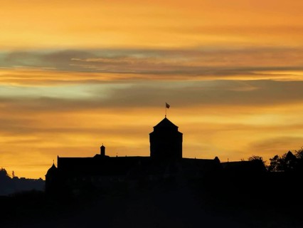 Silhouette of a castle against an orange sky at sunset