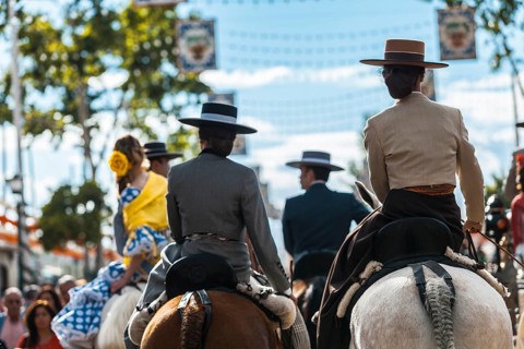 Seville, Spain, Europe. Young women and men in traditional equestrian clothes on horseback during