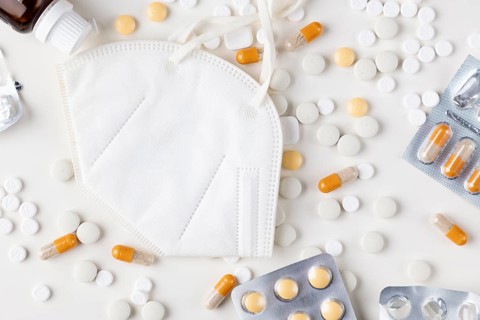 White respirator surrounded by scattered tablets and blister packs