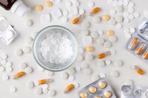 Scattered white tablets and a glass of water on a table