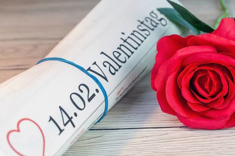 Symbolic newspaper with the title 14.02. VALENTINE'S DAY next to a red rose