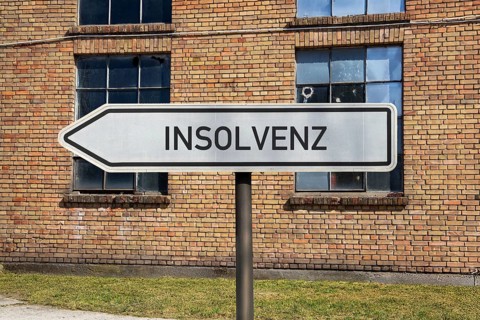 (Photo montage) Directional arrows with the inscription BANKRUPTCY in front of an old industrial