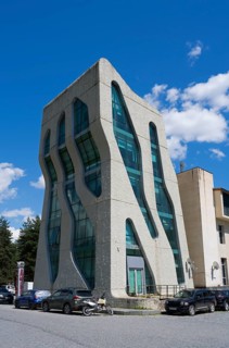 Modern, futuristic building with wavy glass facades and cars in front of it, police station