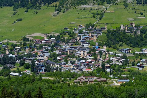 A village with scattered old houses in a green mountain landscape, defensive towers, Mestia,