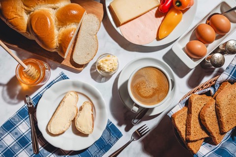 Breakfast with toast, sliced stollen, honey, cheese, ham, coffee, butter, bell pepper and eggs