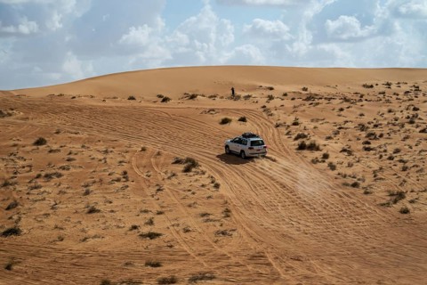 Car drives over sandy road, Wahiba Sands desert, Oman