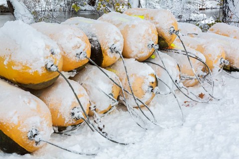 Close-up of stacked yellow cautionary river navigation buoys in storage and covered with winter