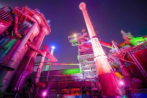 Colour-illuminated industrial ruins at night with pipes and futuristic character, Landschaftspark